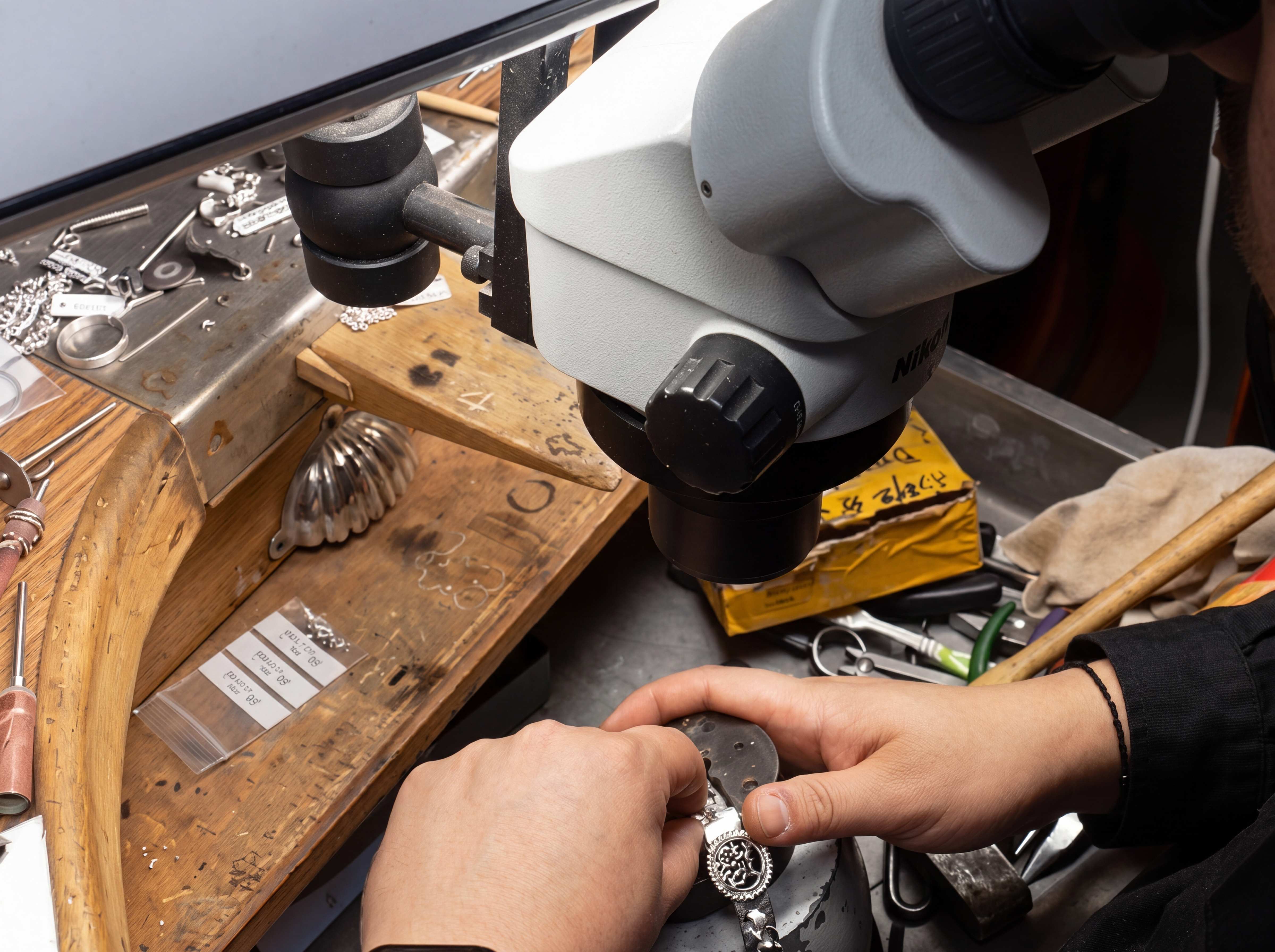 Taller de Joyería Daira en Alcorcón: un joyero trabaja bajo un microscopio Nikon reparando una pieza de plata.